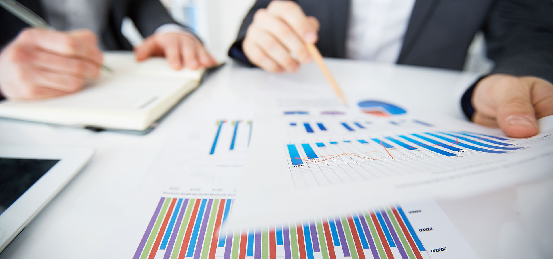 hands holding pencils, while looking over financial charts