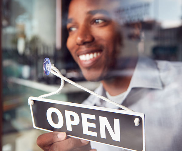 image of man turning a sign in the window to open